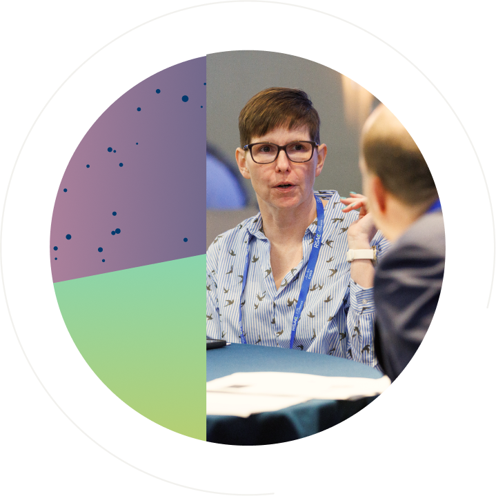 Woman wearing glasses and an RSAC lanyard speaking with another attendee at a networking event, framed by a circular graphic with purple and green geometric patterns.