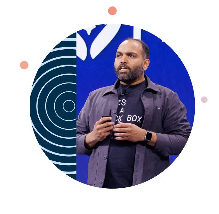 Male speaker holding a presentation remote on stage, framed by a circular design with navy blue concentric rings.