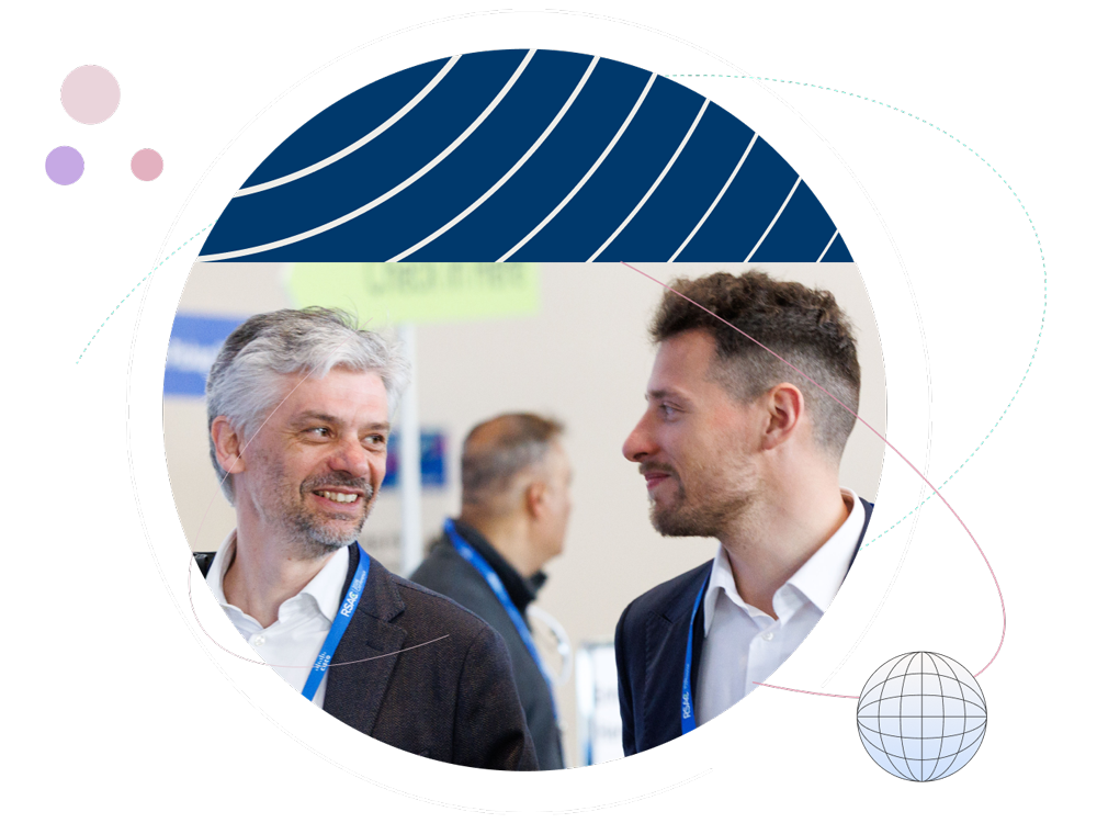 Two male conference attendees wearing blue RSAC lanyards smiling at each other, framed by a circular design with navy blue curved lines and colorful geometric accents.