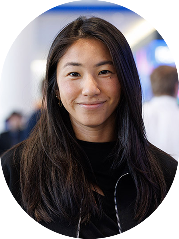 Woman with long dark hair wearing a black jacket at a conference.