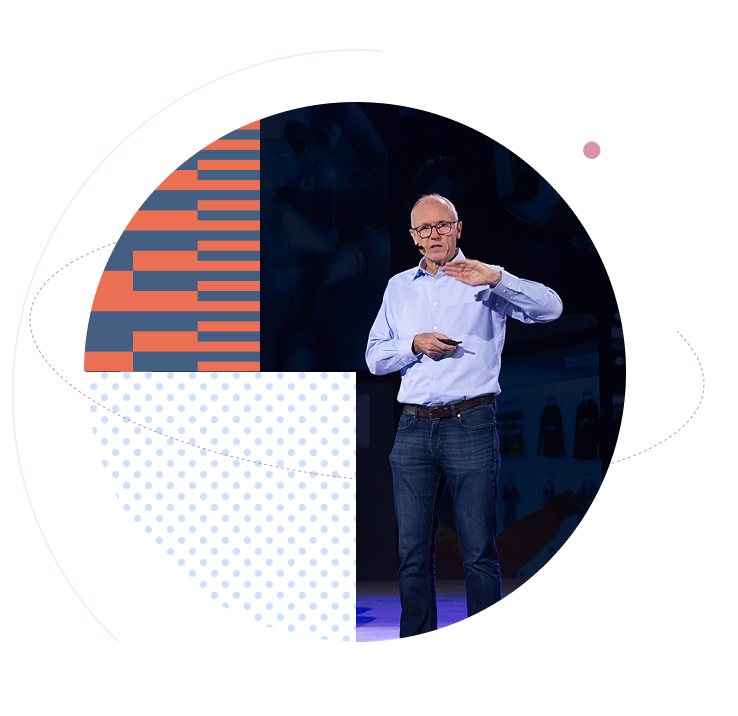 Male presenter speaking on stage with a microphone, framed by orange stripes and blue dotted patterns.