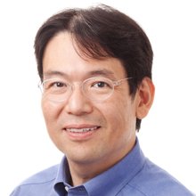 Headshot of Shin Adachi smiling, wearing glasses and a blue collared shirt.