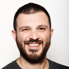 Headshot of Tomer Agayev smiling with short dark hair and a beard.
