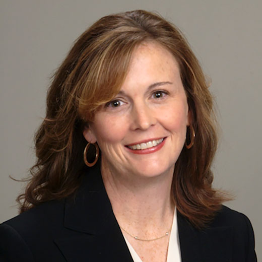 Headshot of Andrea Abell smiling, wearing a black blazer and white shirt.