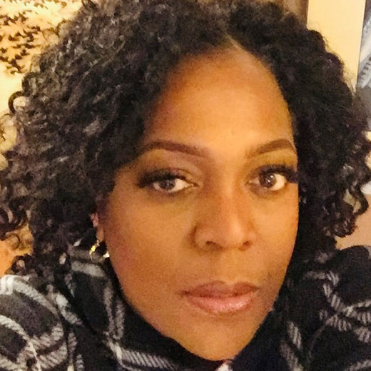 Headshot of Nneka Achufusi with curly dark hair.