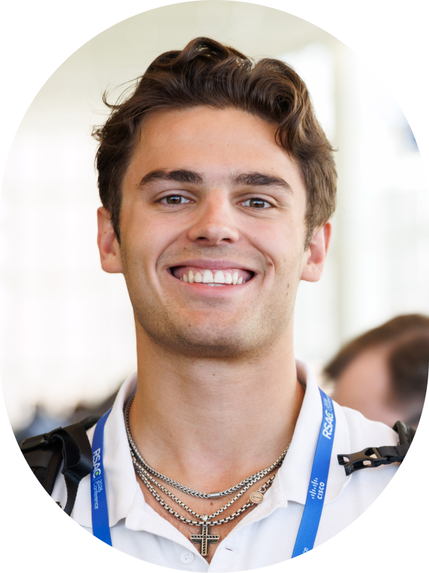 Smiling man with short brown hair wearing a white polo shirt and RSAC conference lanyard.