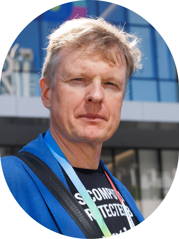 Man with short blond hair wearing a blue jacket and conference badge.