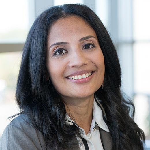 Headshot of Nivedita Aggarwal smiling, wearing a gray blazer and white shirt.