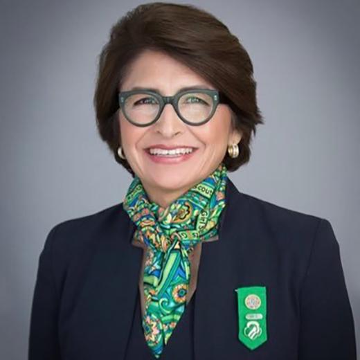 Headshot of Sylvia Acevedo smiling, wearing glasses, a navy blazer, and a colorful scarf.