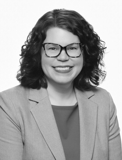 Laura Koetzle: Black-and-white professional headshot of Laura Koetzle smiling, wearing glasses and a blazer.