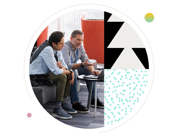 Two male conference attendees seated together, discussing information on a laptop, framed by a circular design with black-and-white geometric patterns and mint green accents.