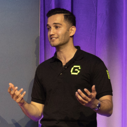 Male speaker wearing a black polo shirt presenting on stage, representing Guardrail.AI, a 2023 RSAC Launch Pad finalist acquired by RAIN Crypto.