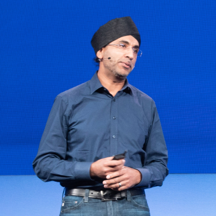 Male speaker wearing a black turban and blue button-down shirt presenting on stage, representing the 2019 RSAC Launch Pad finalist acquired by Acquihire (Apple).