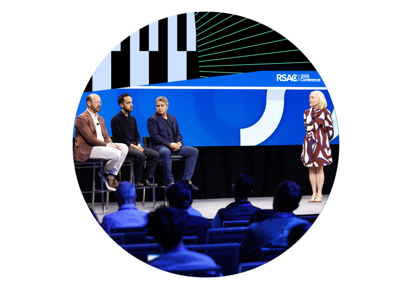 Three male panelists seated on stage alongside a female moderator speaking at RSAC Conference 2026, with audience members watching.